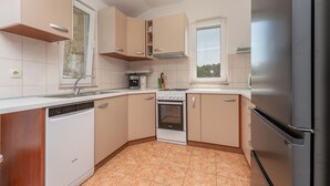 A compact kitchen with a dishwasher, stove, oven, and a refrigerator. - Stunning apartment in Ugrinic with WiFi (Ugrinic)
