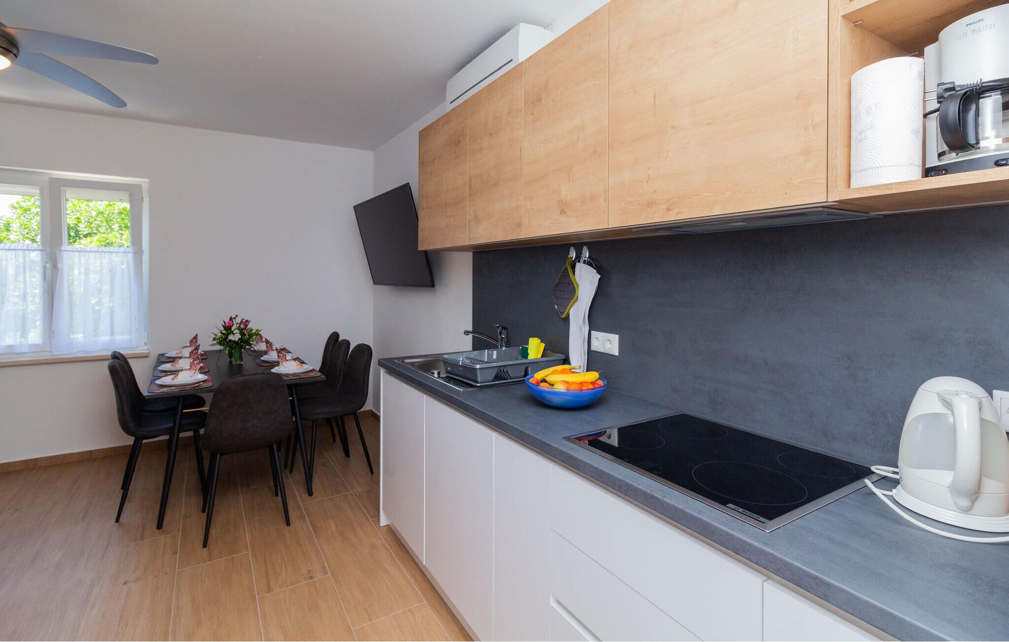 A modern kitchen with a built-in stove, a sink, and a dining area with a table set for four.