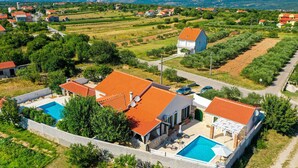 Una villa con piscina, rodeada de exuberante vegetación y un imponente paisaje montañoso.