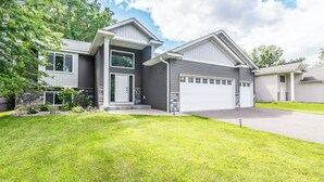 A modern two-story house with a garage, a well-maintained lawn, and a stone accent wall.