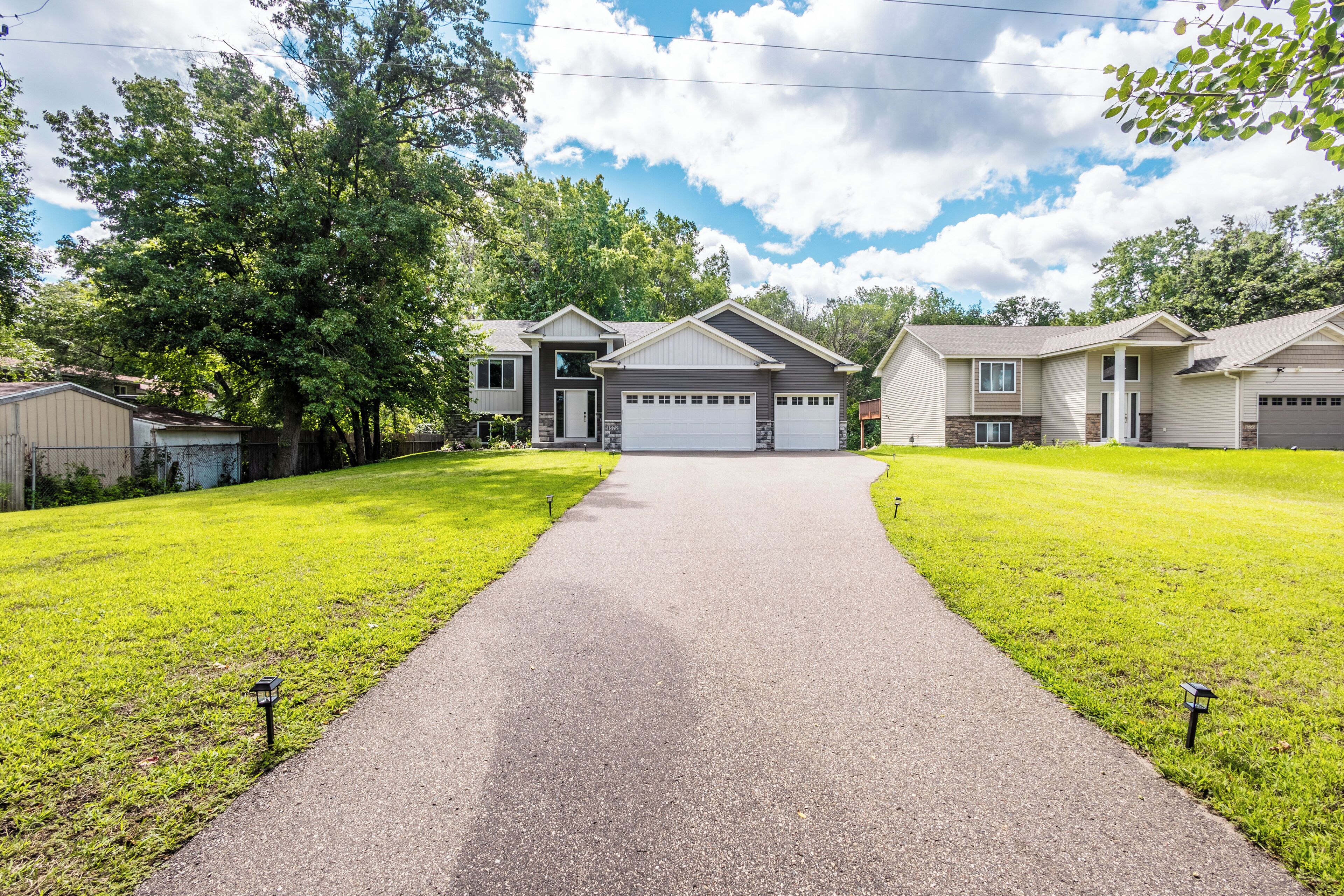 A residential area with a paved driveway leading to a house with a garage.