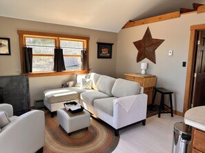Un salon chaleureux avec un canapé, une table basse et une décoration en forme d’étoile au mur.
