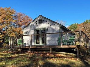 A white wooden house with a porch and a covered deck area.