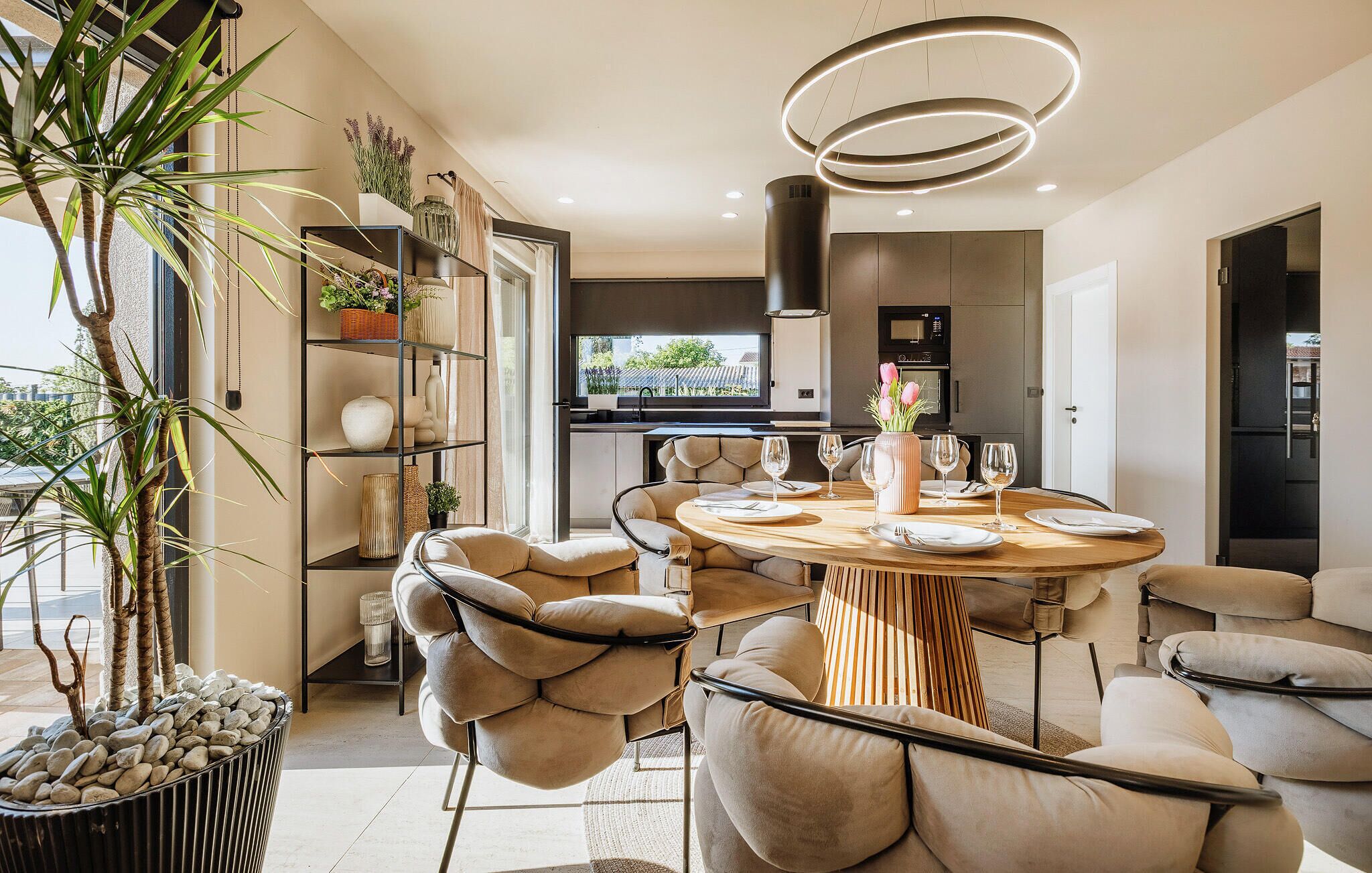 Un espace repas moderne avec une table ronde, des chaises rembourrées et un luminaire central.