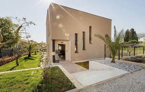 A modern building with a flat facade, a small entrance, and a well-maintained garden with grass and shrubs. - Nice Home In Tar With Private Swimming Pool (Tar)
