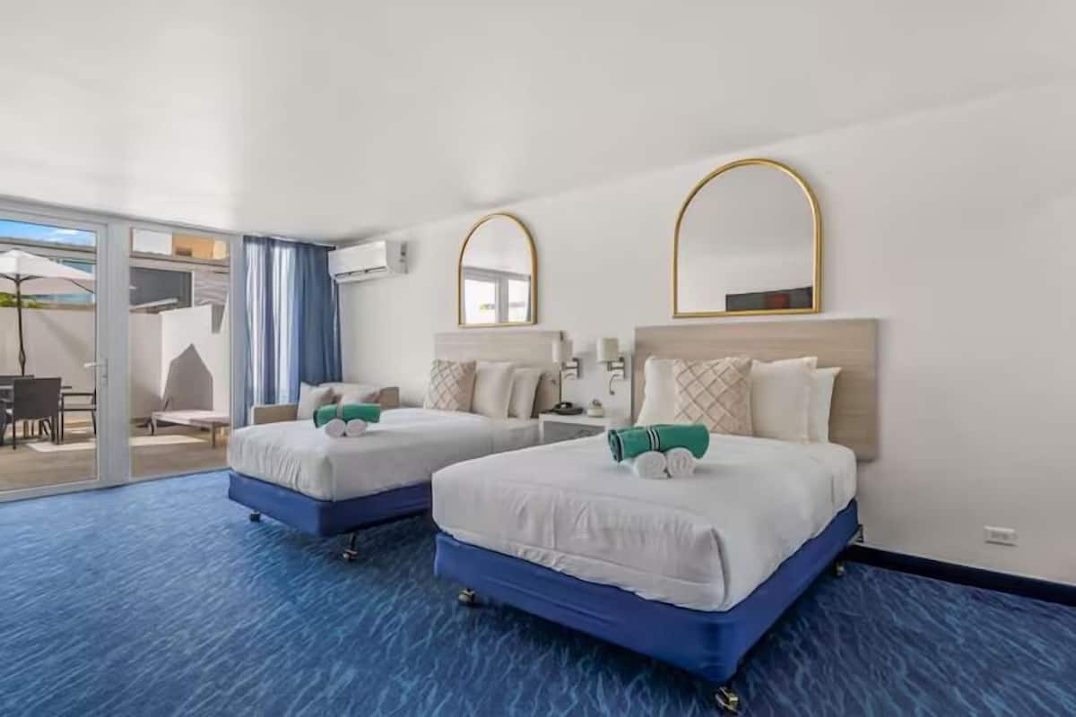 Ein Hotelzimmer mit zwei Betten, einem großen Fenster und Blick ins Freie.