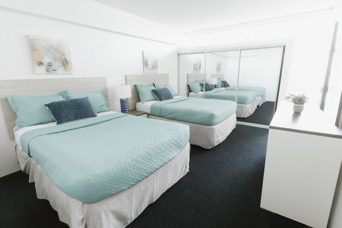 Ein Hotelzimmer mit zwei Betten, einem großen Spiegel und einem Schreibtisch.