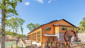 Un bâtiment en bois doté de grandes fenêtres, d’un mur en pierre et d’une roue à eau en bois.
