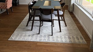 Een eetruimte met een tafel en stoelen, een kroonluchter en uitzicht op de omgeving via een deur.
