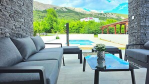 A patio area with stone walls, a pool, and outdoor seating. - Awesome home in Baska (Baska)
