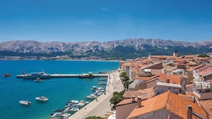 A coastal town with a marina, buildings with red-tiled roofs, and mountains in the background. - Awesome home in Baska (Baska)