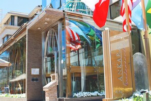 A hotel entrance with a glass facade, a brick structure, and a sign indicating the hotel name. - HOTEL RESTAURANTE ANKARA (Vina del Mar)