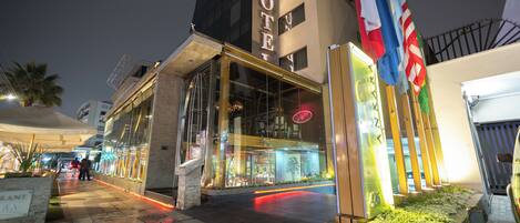 A hotel with a glass facade, a sign reading "HOTEL", and multiple flags.