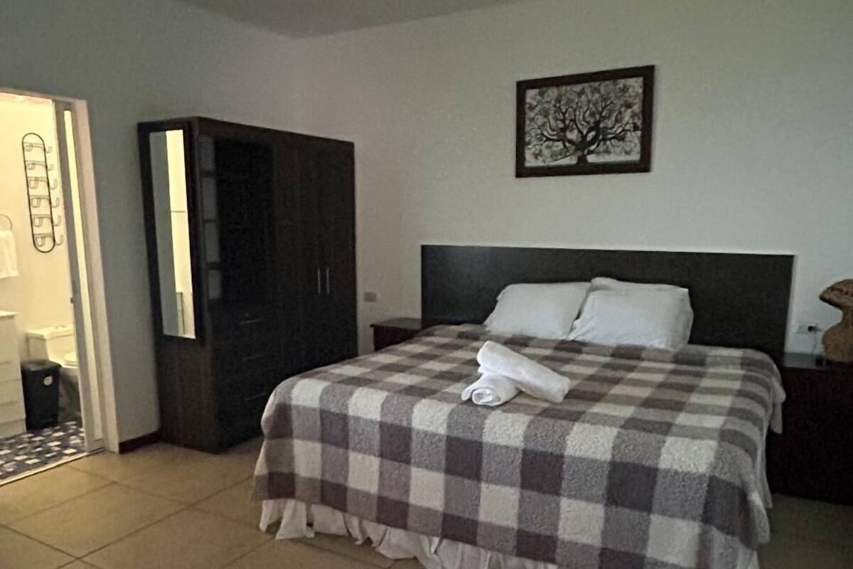 A bedroom with a bed, a wardrobe, a nightstand, and a painting on the wall.