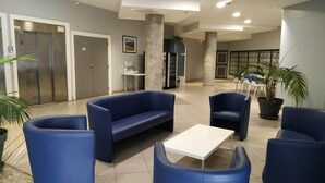 A lobby with blue seating, a white table, and a reception area with a counter and chairs. - Vacation apartment with swimming pool & 400m from the beach (Vallauris)