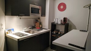 A compact kitchen with a sink, stove, microwave, and a small dining area. - Vacation apartment with swimming pool & 400m from the beach (Vallauris)