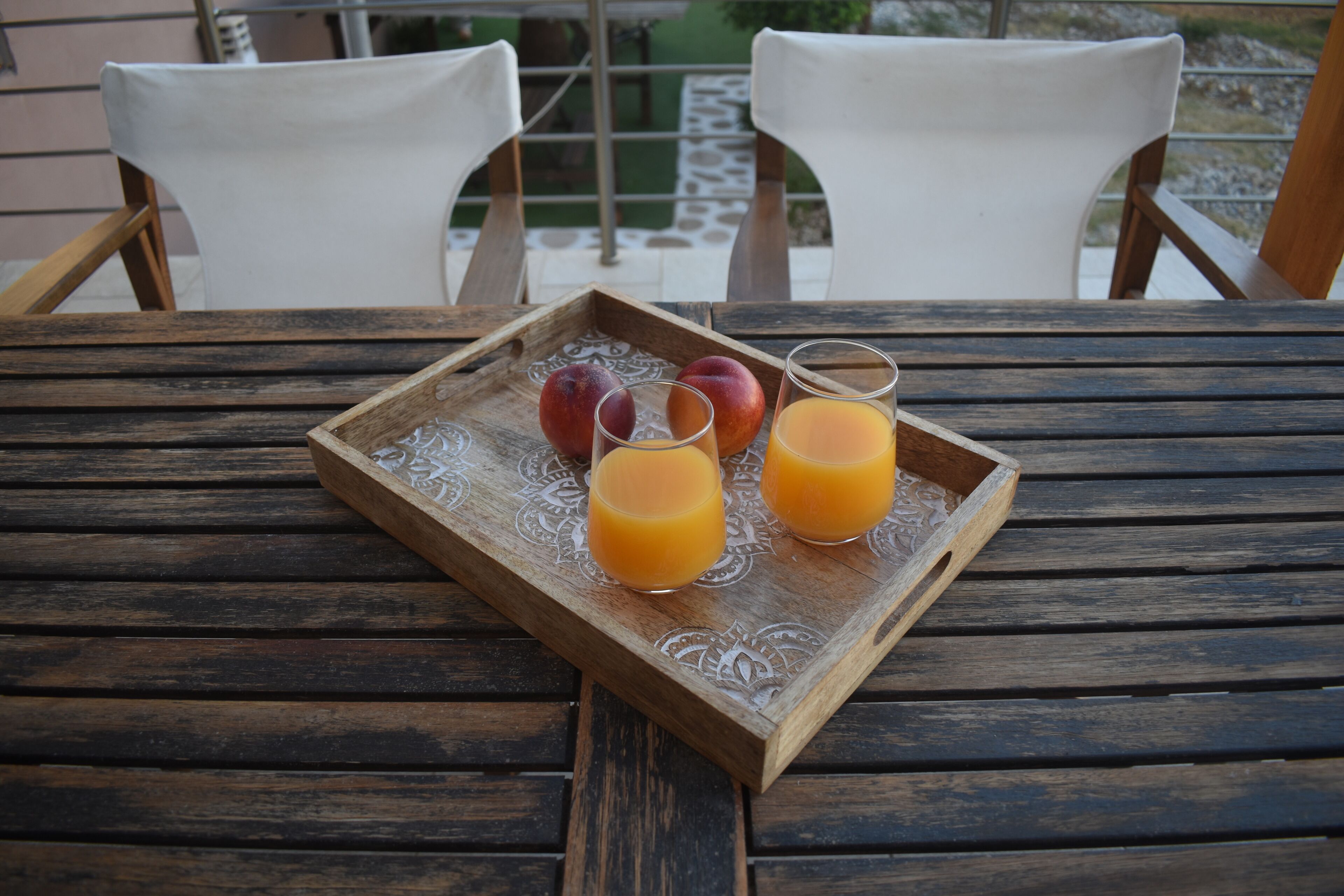 A wooden tray with fruit and juice on a table.