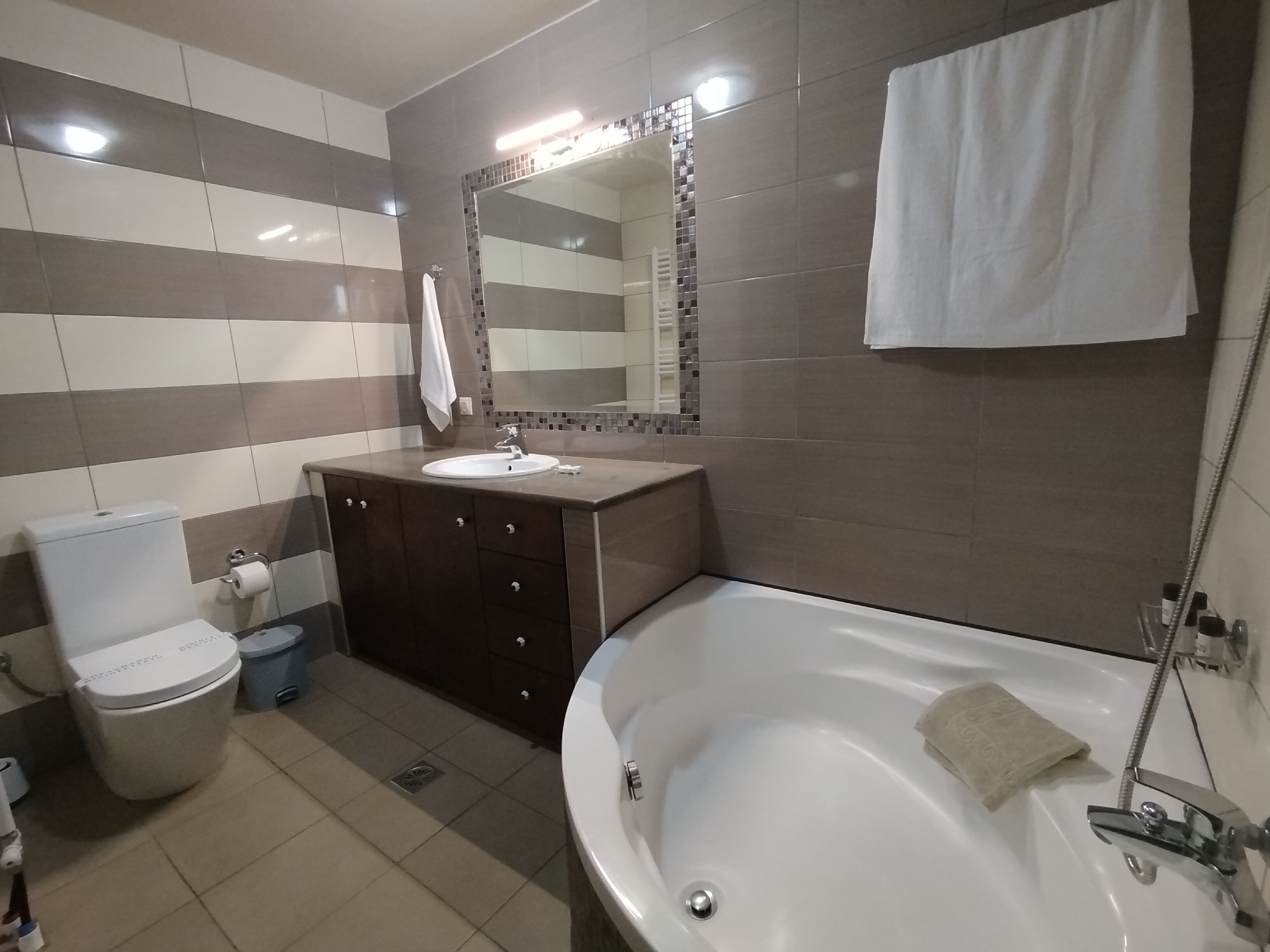 A bathroom with a toilet, sink, vanity, and bathtub.