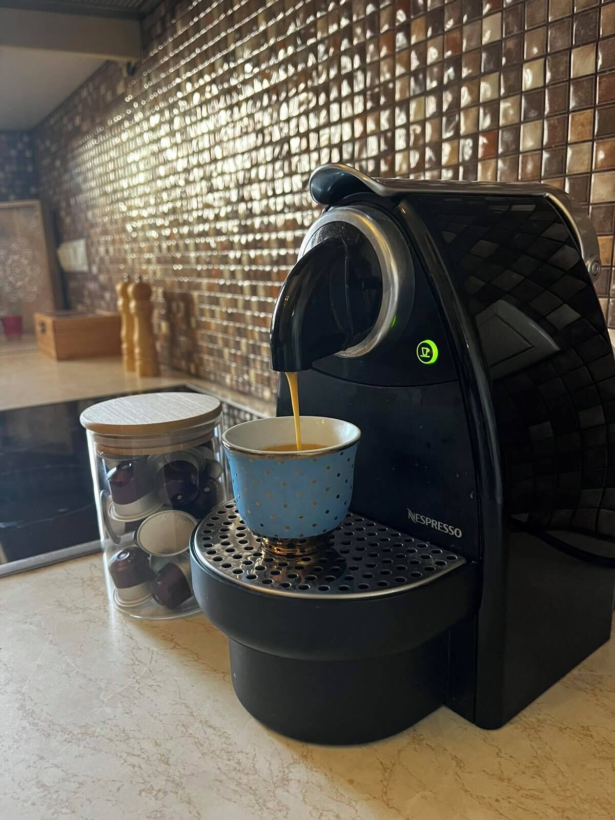 A Nespresso coffee machine dispensing coffee into a blue cup.