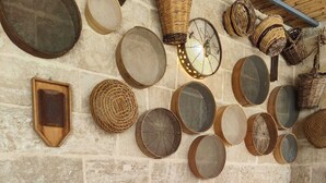 A stone wall with various woven baskets and circular mirrors.