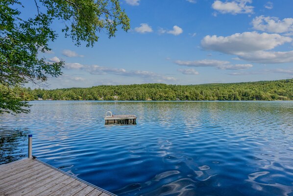 A wooden dock extending into a calm lake with a clear sky above.
