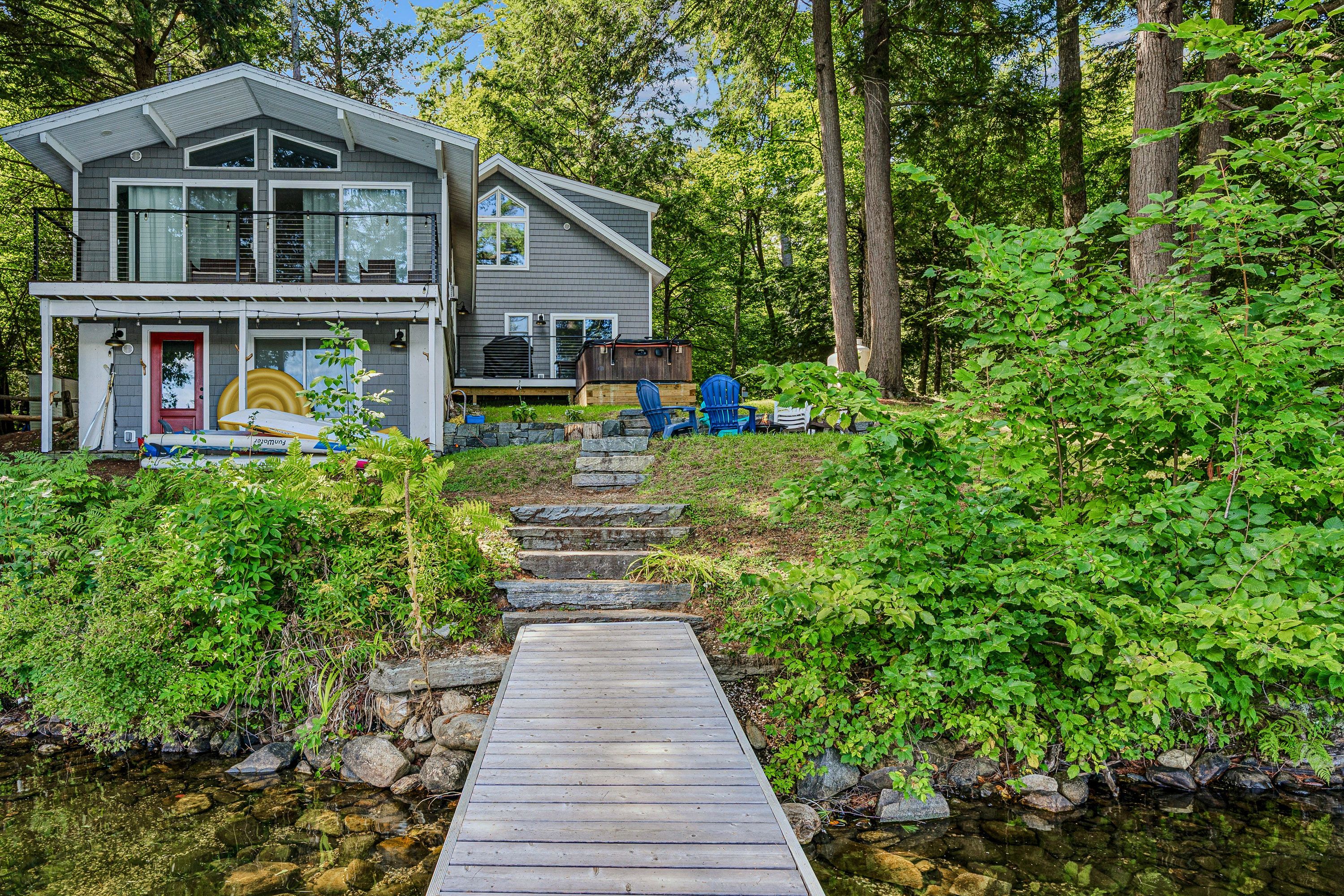 A two-story house with a dock leading to a small stream.