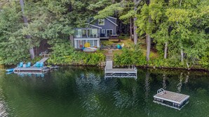 A lakeside property with a house, dock, and boats. - Lakefront Cottage w/ Hot Tub & Dock on Lake Rescue (Ludlow)