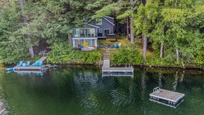 A lakeside property with a house, dock, and boats. - Lakefront Cottage w/ Hot Tub & Dock on Lake Rescue (Ludlow)