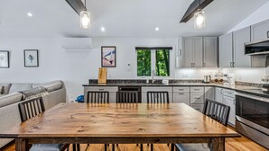 A modern kitchen with a wooden dining table, grey cabinets, and a large window. - Lakefront Cottage w/ Hot Tub & Dock on Lake Rescue (Ludlow)
