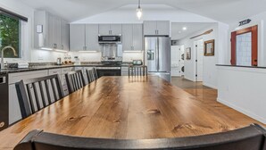 A modern kitchen with a large island, stainless steel appliances, and a dining area with a wooden table. - Lakefront Cottage w/ Hot Tub & Dock on Lake Rescue (Ludlow)