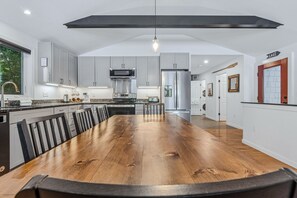 A modern kitchen with a large island, stainless steel appliances, and a dining area with a wooden table.