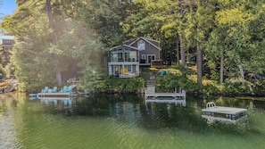 A lakeside house with a dock, outdoor seating, and a boat.