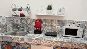 A kitchen with a sink, a red coffee machine, a white microwave, and a patterned backsplash. - Cristofaro home 2 (Palermo)