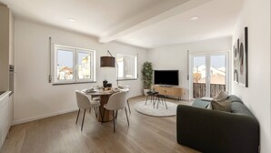 Un salon moderne comprenant un coin repas, un téléviseur à écran plat et un canapé.
