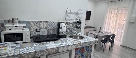 A modern kitchen with a microwave, coffee maker, and sink.