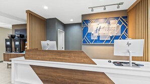 Modernilla designilla varustettu hotellin vastaanottotiski, jossa on digitaalinen näyttö ja Holiday Inn Express & Suites -kyltti.