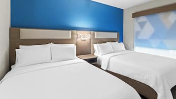 Habitación de hotel con dos camas, una pared de acento azul y una persiana con diseño geométrico.