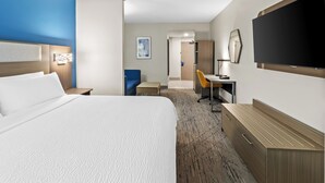 Hotellihuone, jossa on suuri sänky, työpöytä, tuoli, televisio ja vaatekaappi.