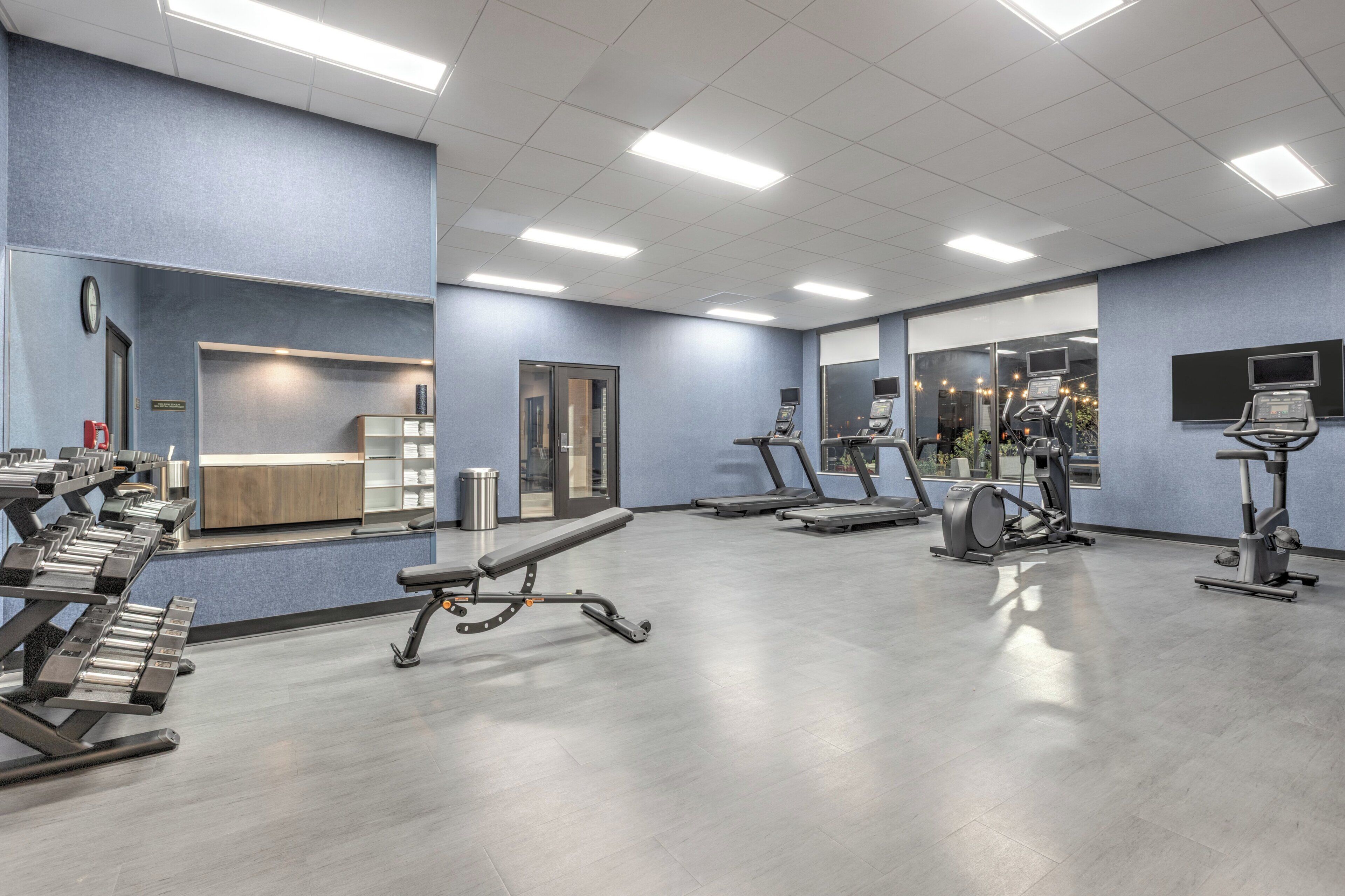 Une salle de sport équipée de tapis de course, d’appareils elliptiques et de bancs de musculation.