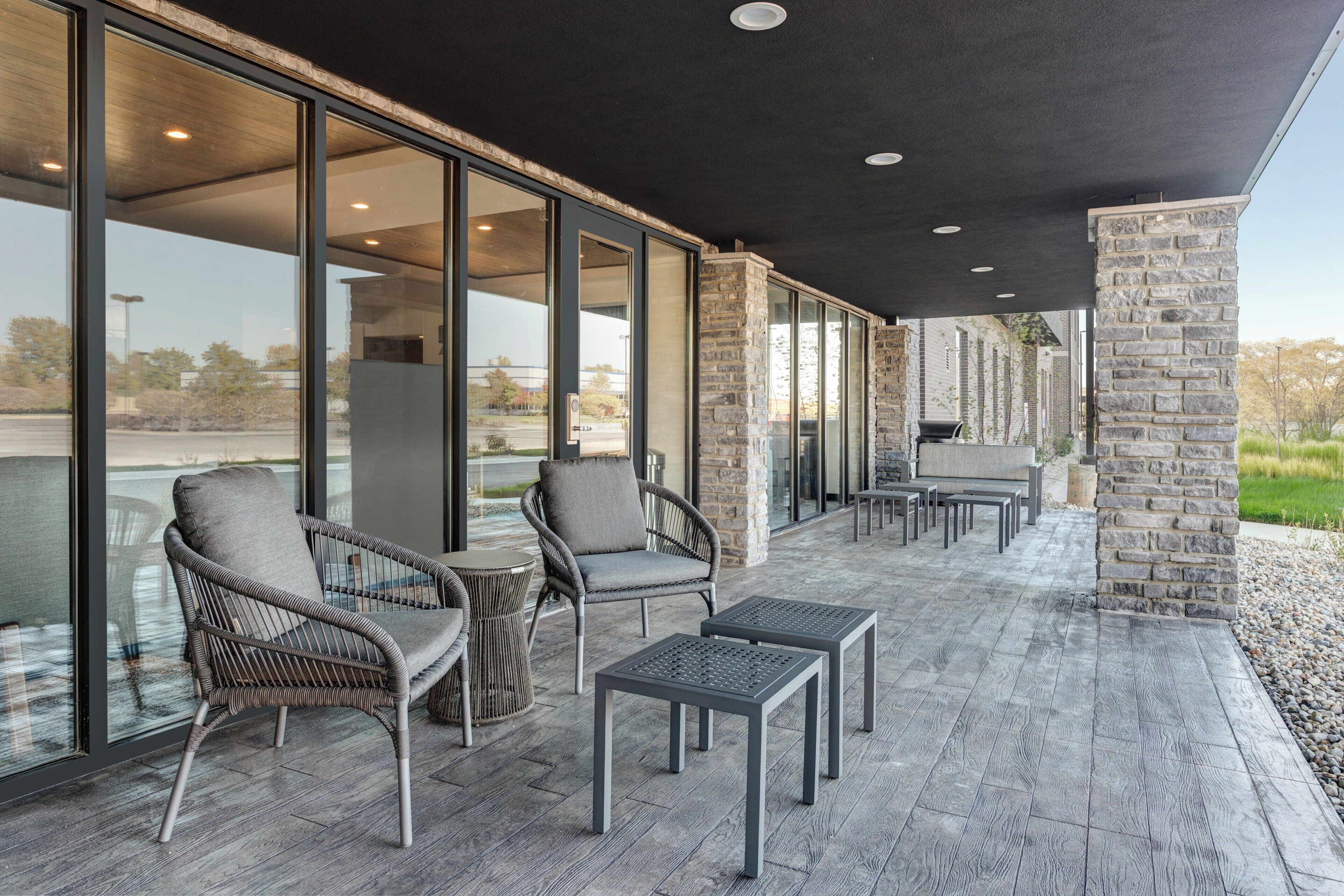 An outdoor patio with wicker chairs, tables, and a stone wall.