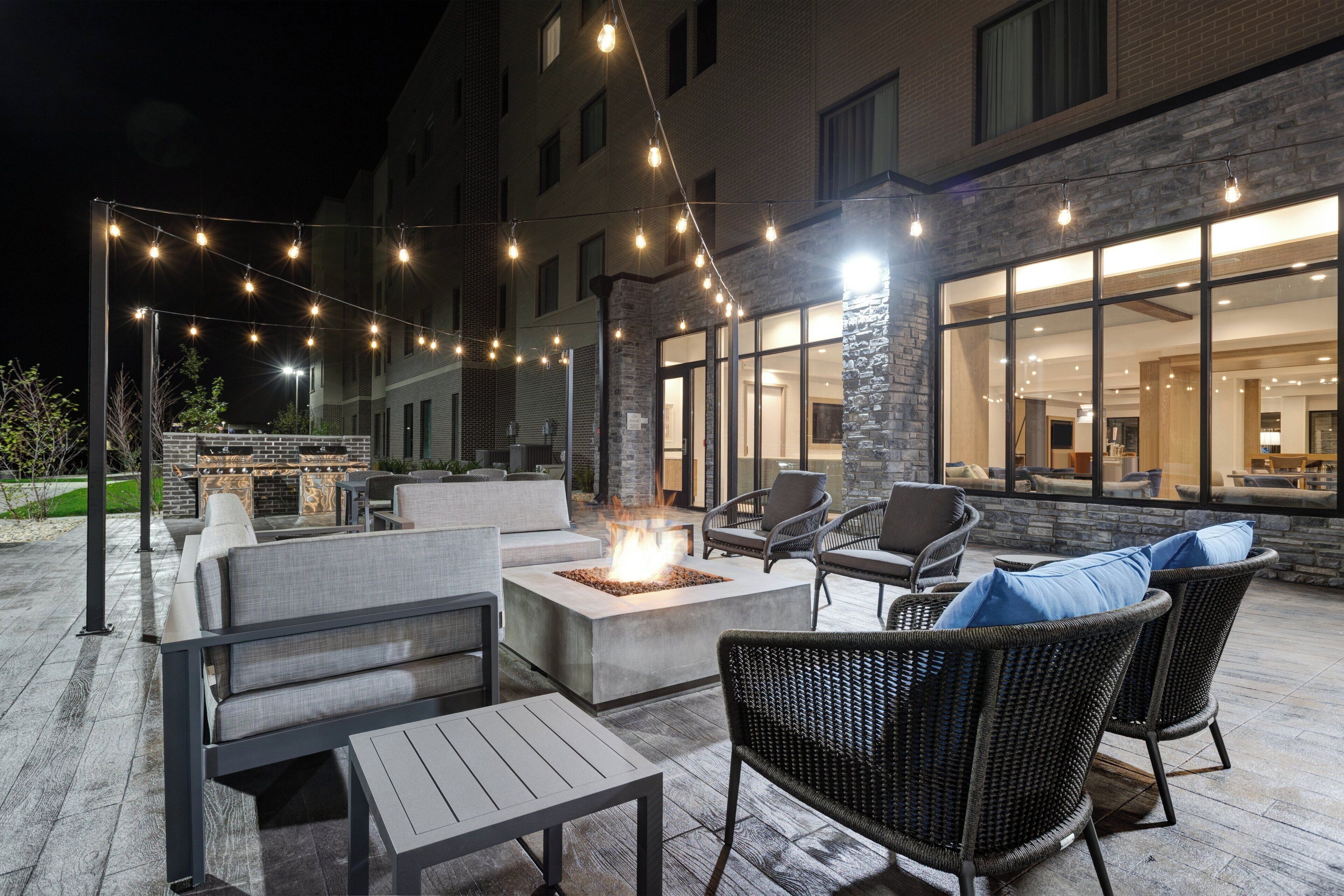 Un patio al aire libre con asientos, una chimenea y luces colgantes.