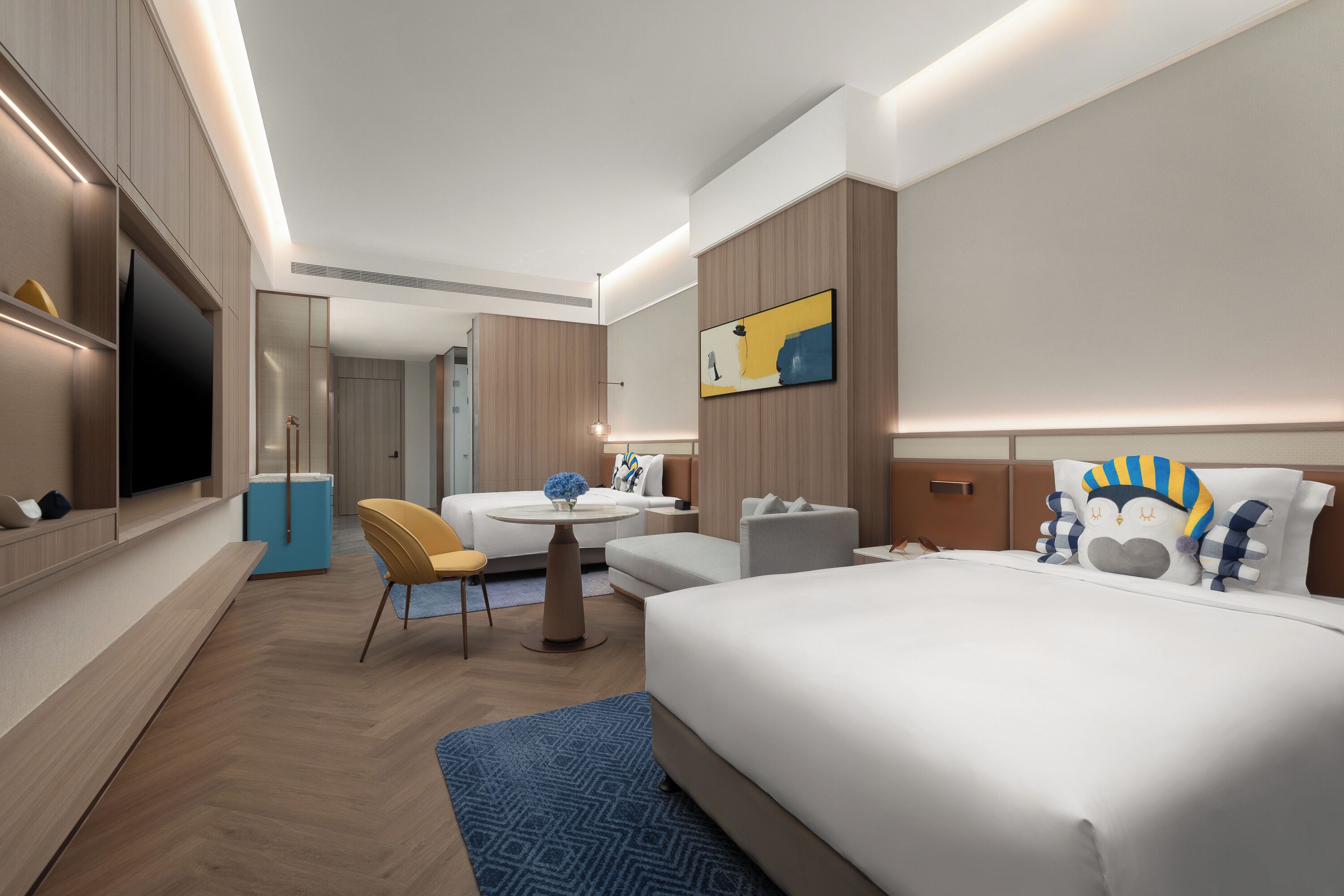 A modern hotel room with a large bed, a desk, a chair, a TV, and a bathroom.