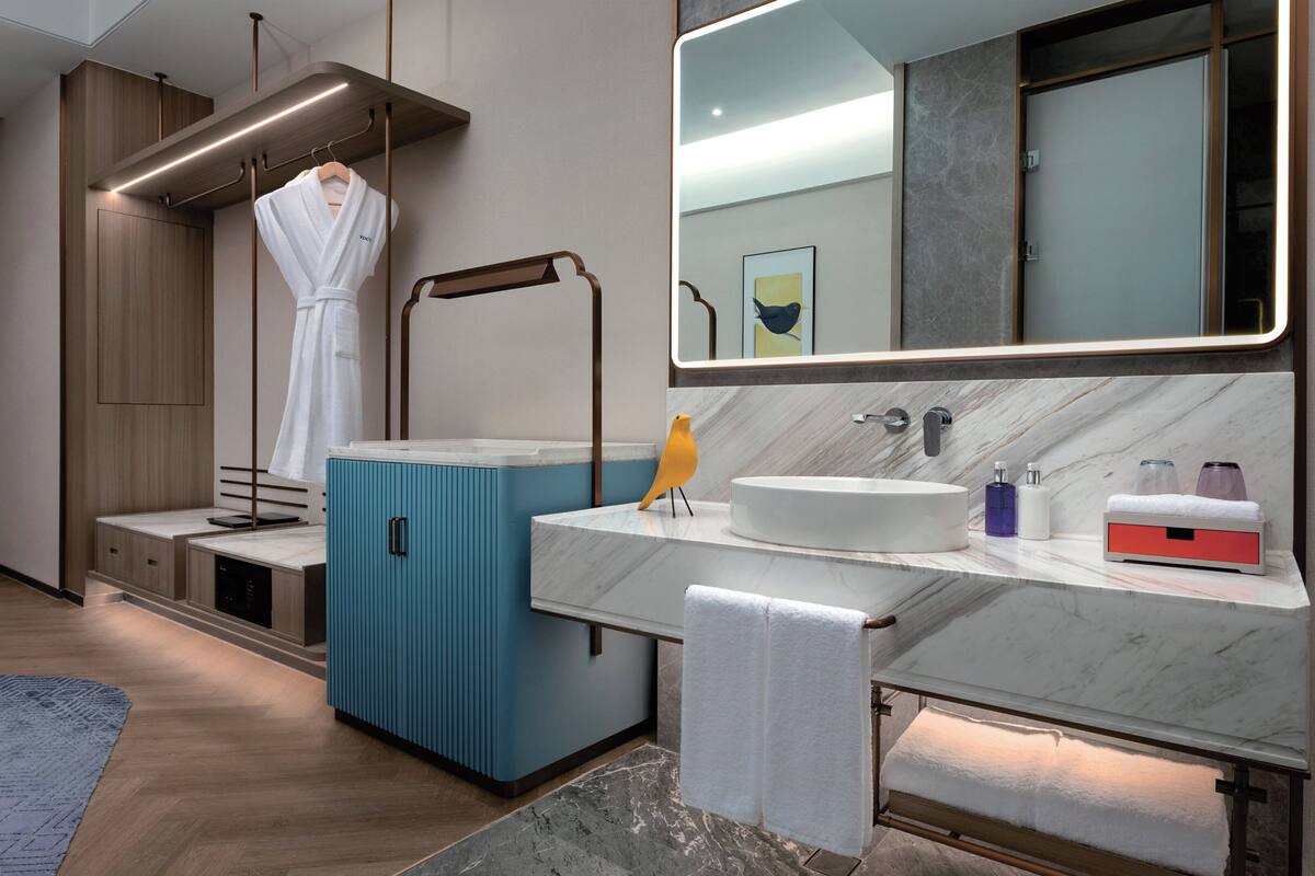 A modern bathroom with a wooden vanity, a blue cabinet, a sink with a marble countertop, and a towel rack.