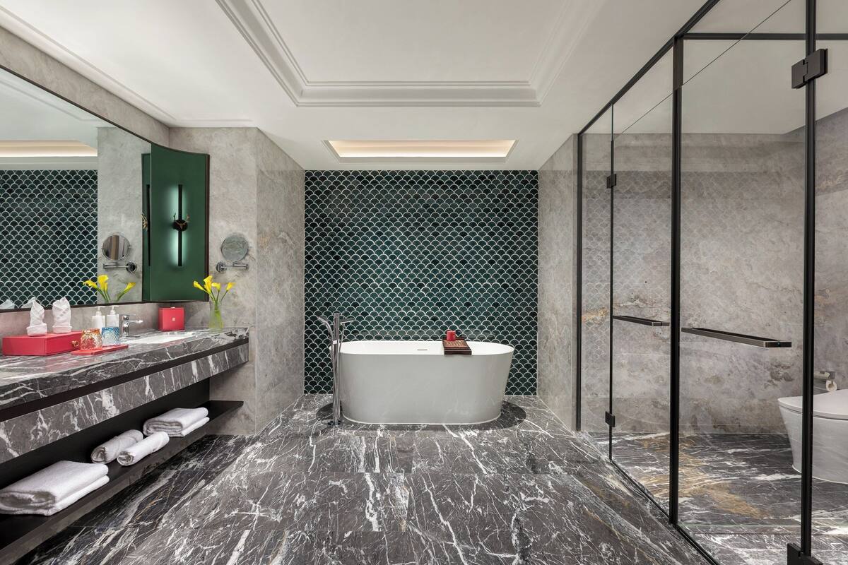 Ein modernes Badezimmer mit freistehender Badewanne, Marmorboden und einer Duschkabine aus Glas.