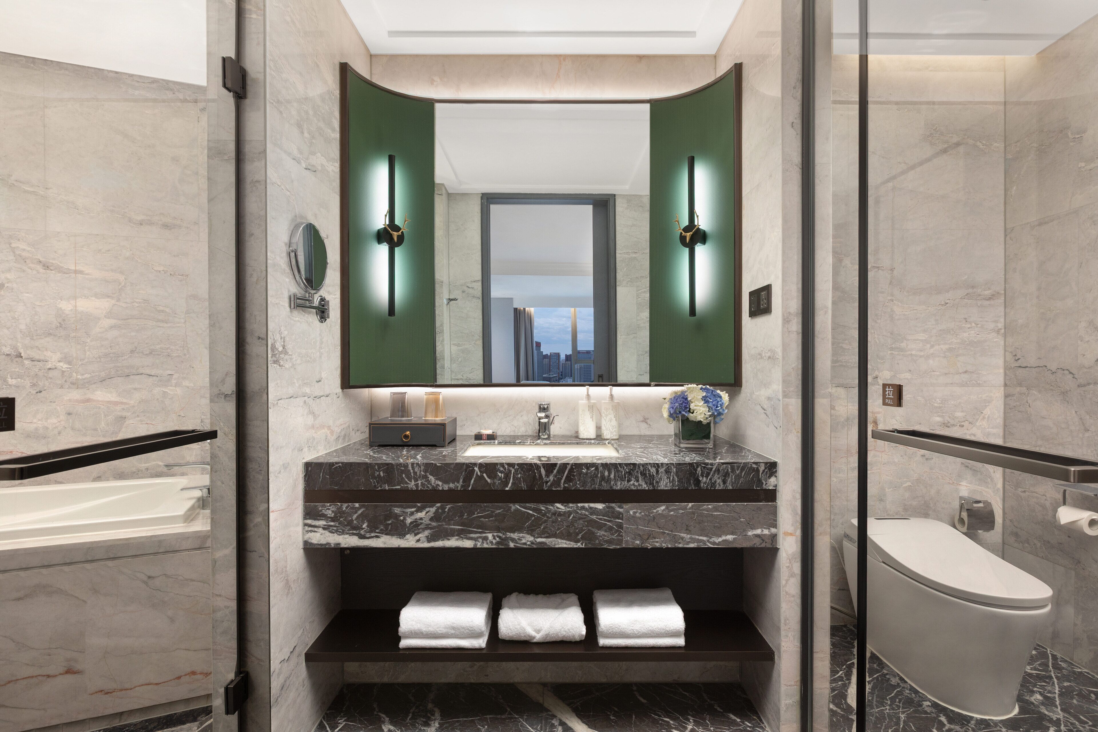 A modern bathroom with a marble sink, a large mirror, and a toilet.