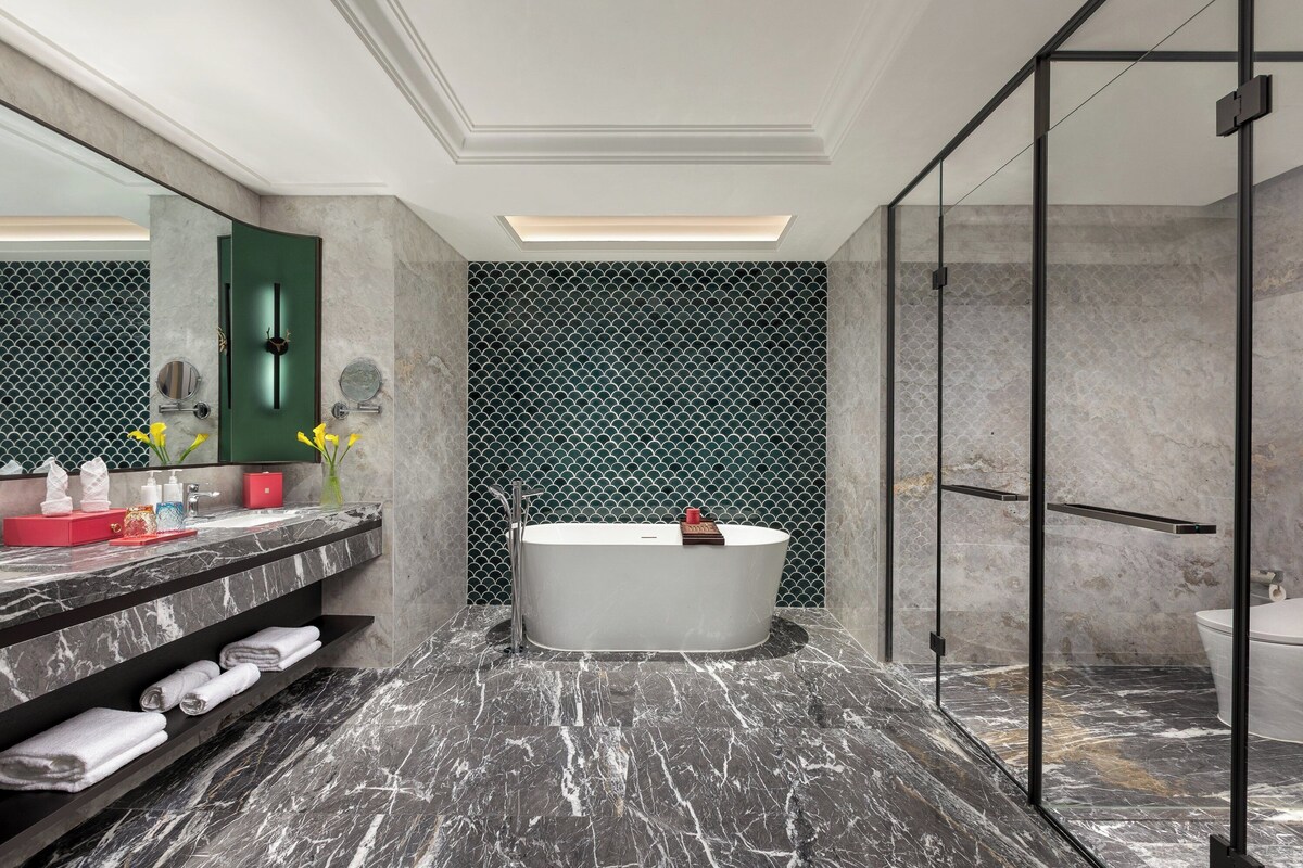 A modern bathroom with a freestanding bathtub, marble flooring, and a glass shower enclosure.