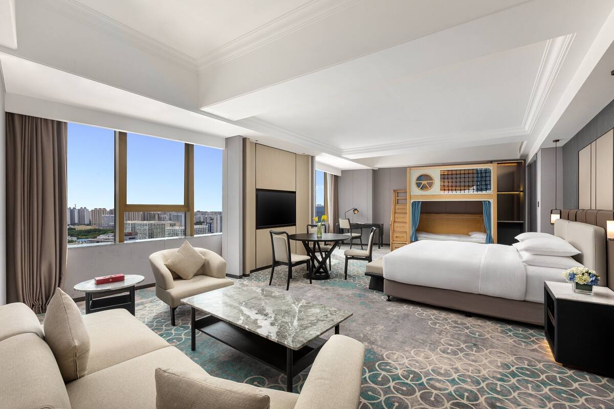 Ein Hotelzimmer mit einem großen Bett, einem Schreibtisch, einer Couch und einem Fernseher.