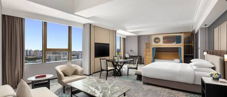 A hotel room with a large bed, a desk, a sofa, and a TV.