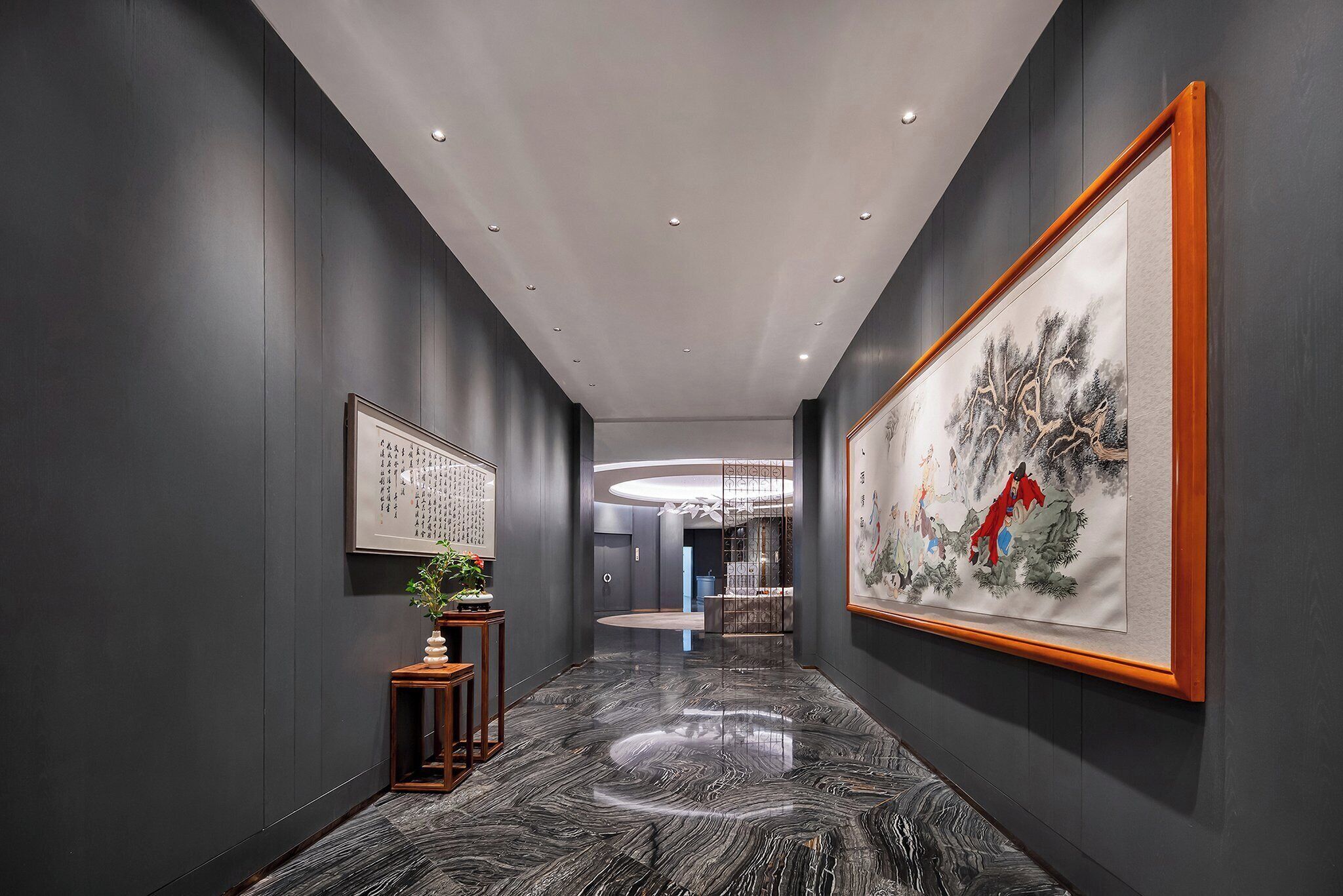 A hallway with dark walls, a marble floor, and framed artwork.