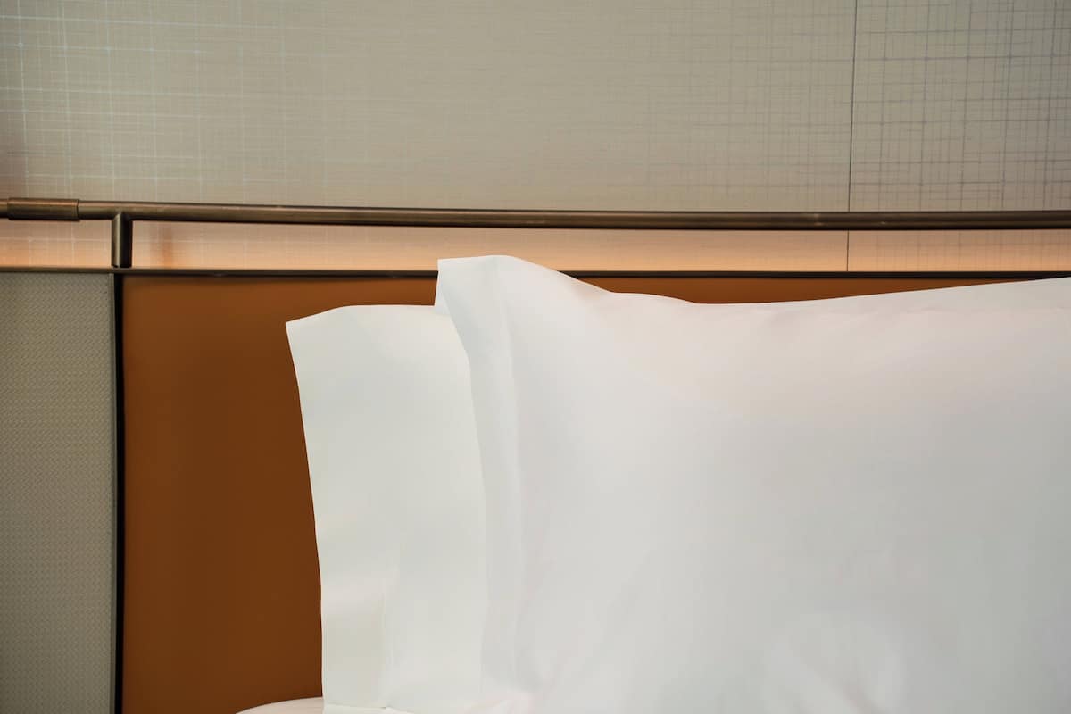Una habitación de hotel con una cama, cabecera y pared con diseño de cuadrícula.